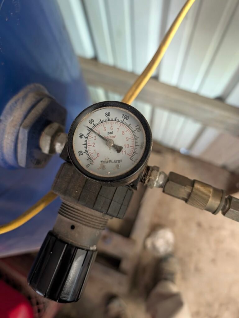 Air compressor pressure regulator dialed to 50 PSI for spraying paint