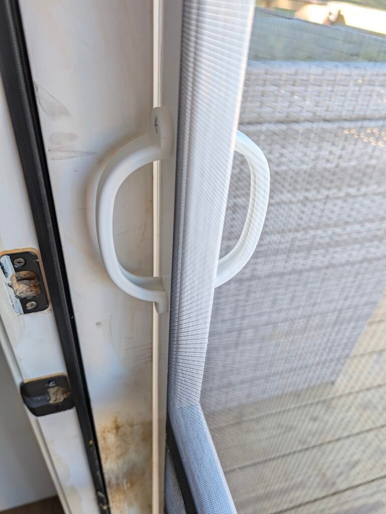 Interior and exterior white pull handles mounted on a vinyl screen door frame